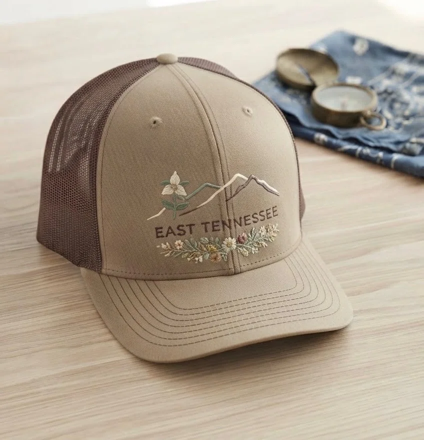 Warm tan and brown trucker hat embroidered with East Tennessee mountains, trillium, and wildflowers