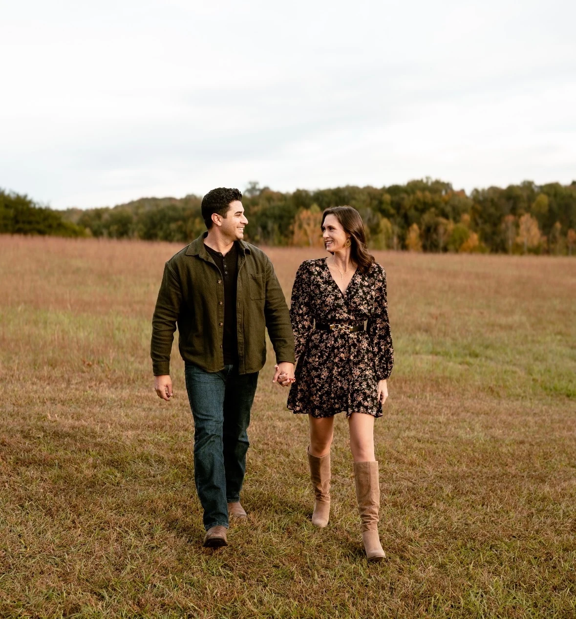 A couple walking hand in hand through an East Tennessee field in autumn