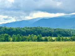 A green field opening toward the Smoky Mountains